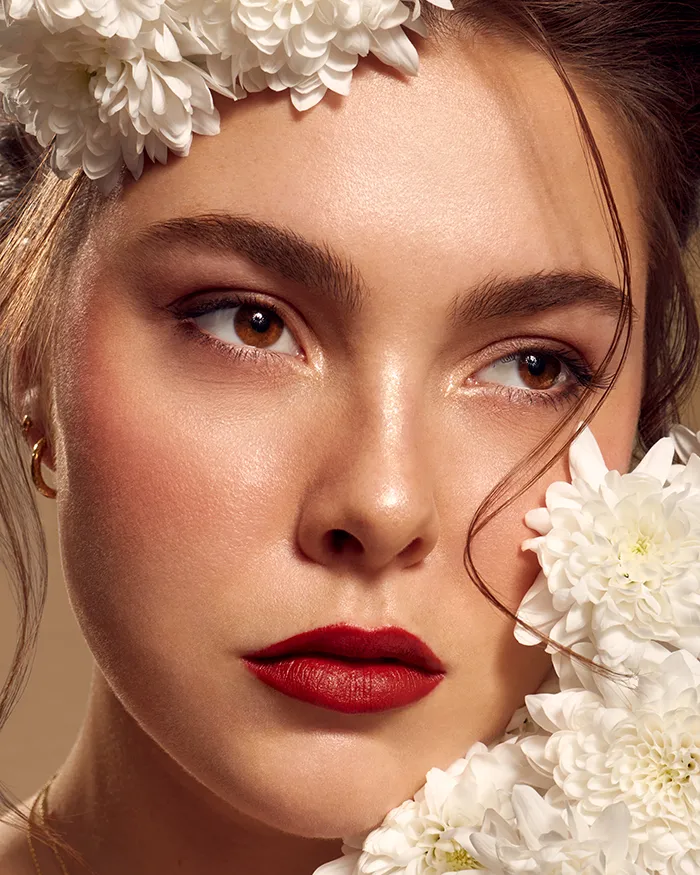 Nahaufnahme Beauty Bild einer Frau mit rotem Lippenstift und weißen Blumen die das Gesicht rahmen