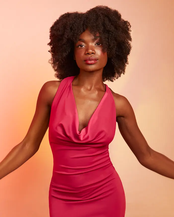 dunkelhäutige Frau mit natürlichen Afrolocken in einem pinken Kleid