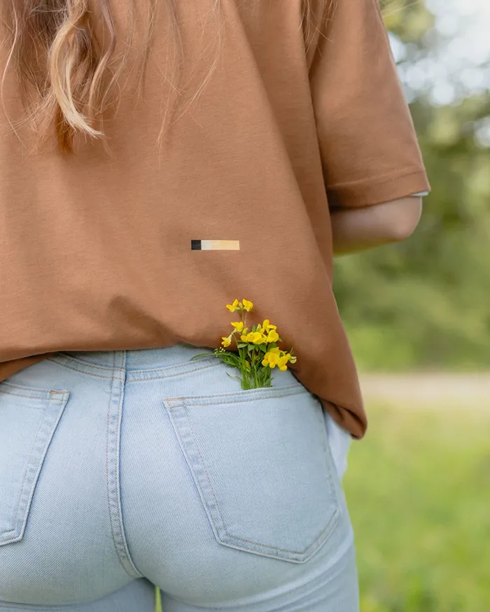 Nahaufnahme eines T-Shirts mit kleinem gelbem Print und gelben Blumen in der hintertasche ihrer Hose